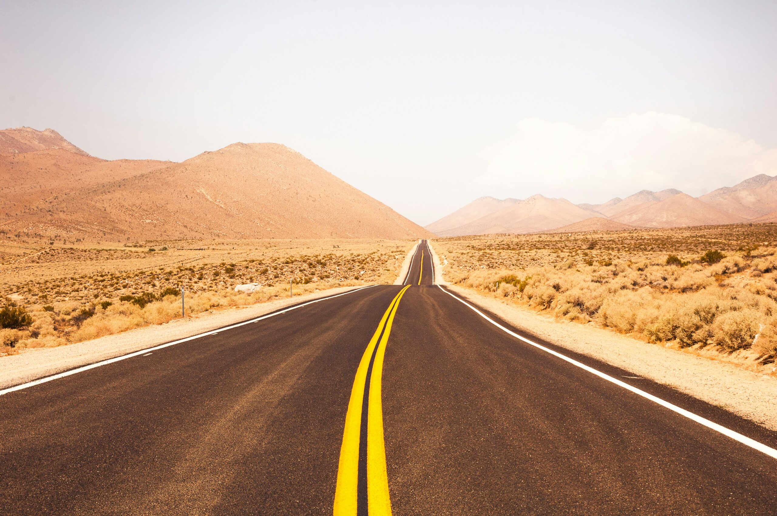 Empty road surrounded by the desert on a sunny day.