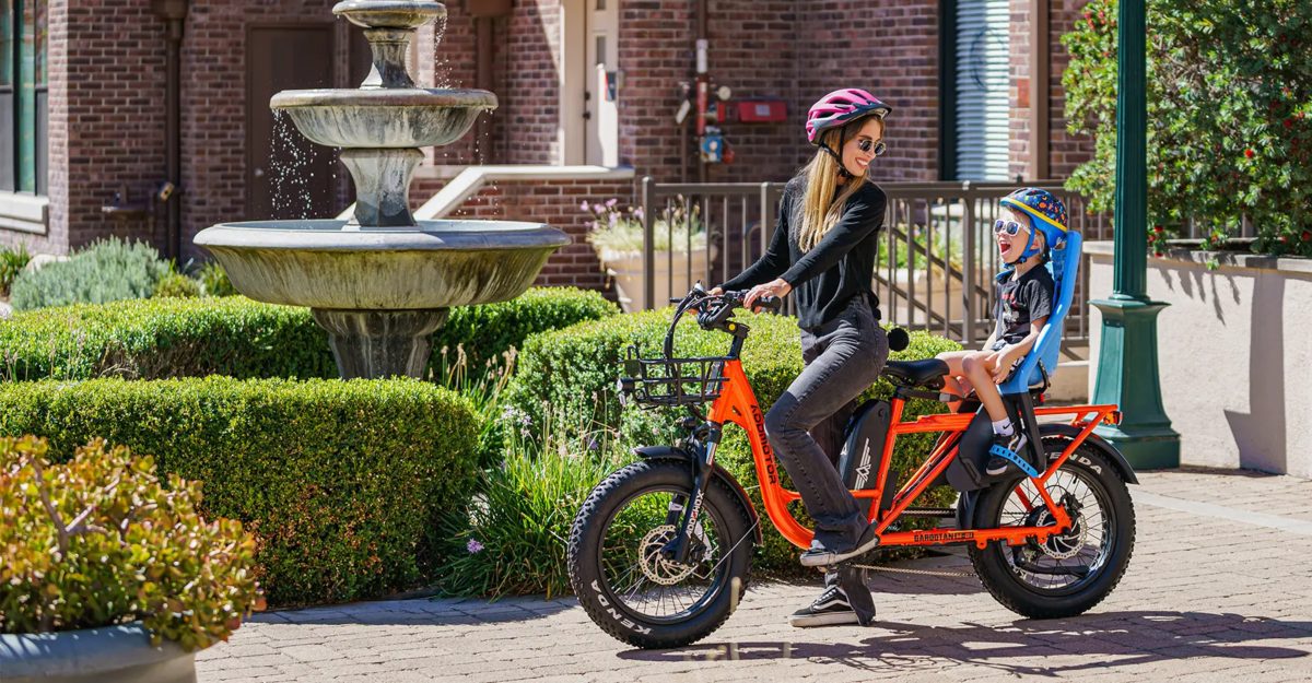 Women riding cargo electric bike with a child.