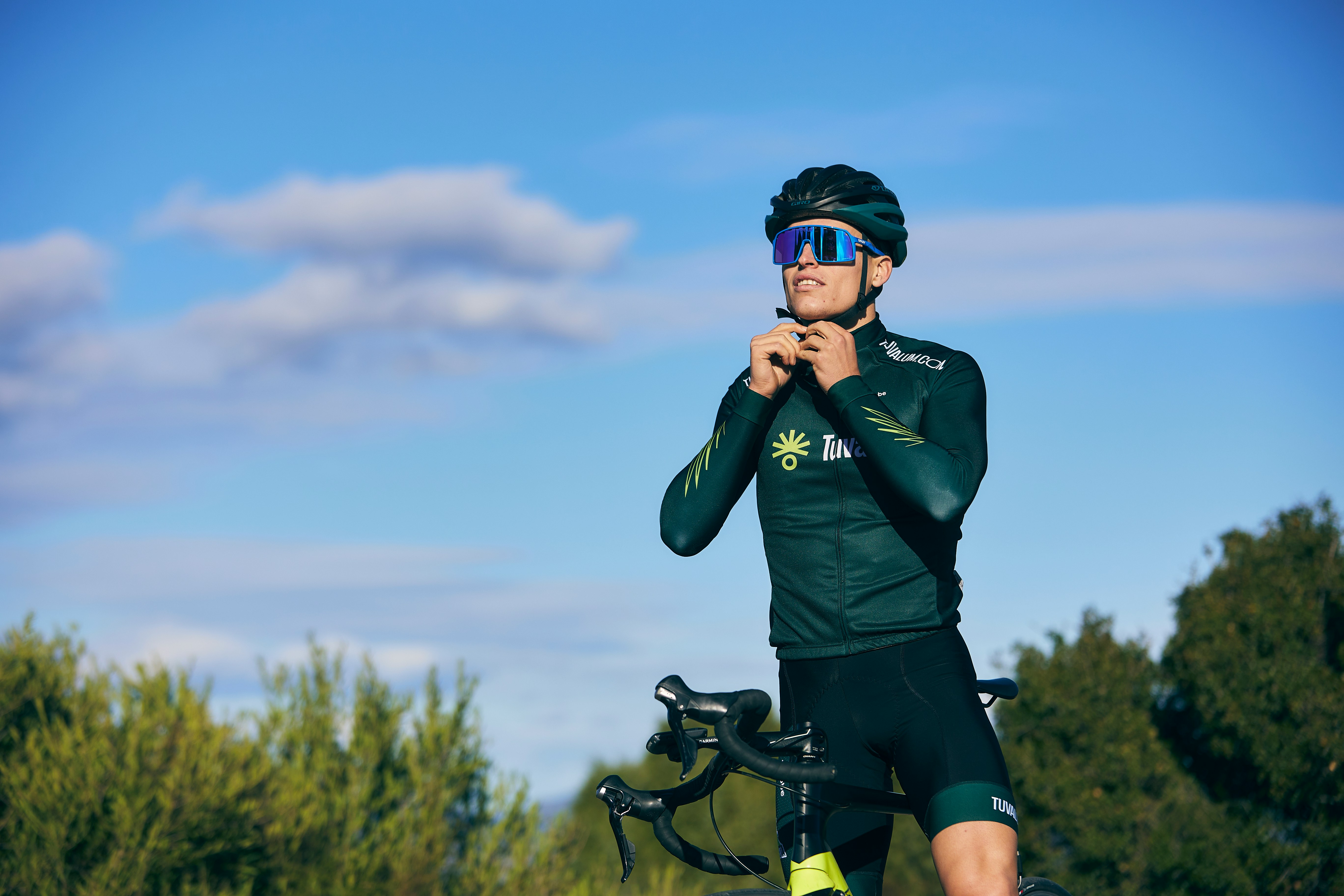 Cyclist with a bike helmet beside a bike in nature.
